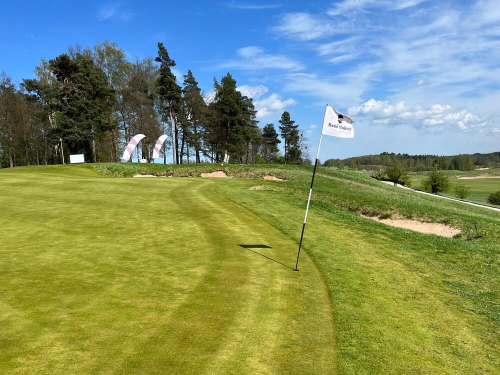 Golfgreen med flag og en golfbunker i baggrunden – her kan du score en birdie