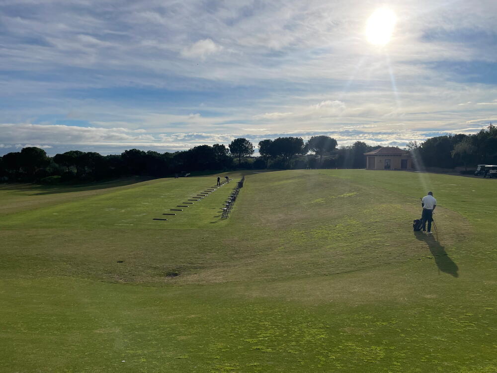 Golfspillere øver slag på driving range i lav sol