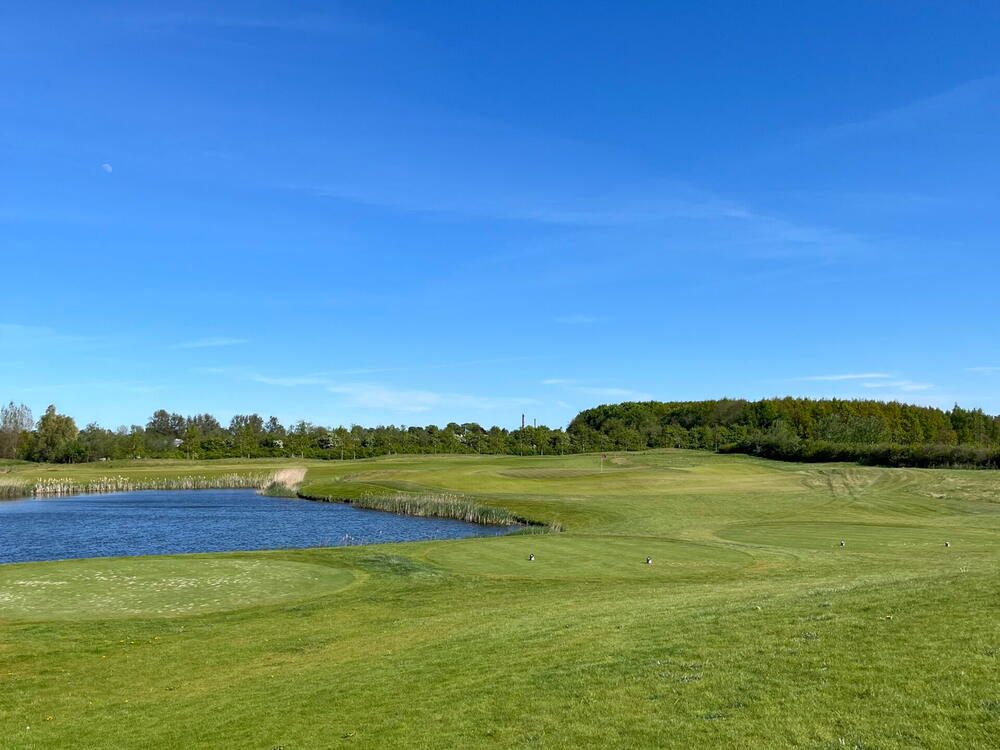 Fairway langs en sø under blå himmel